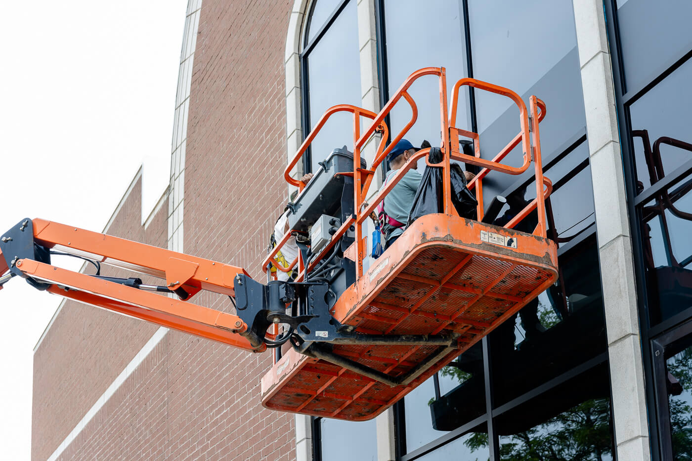 Professional glazing technician installing commercial windows from boom lift
